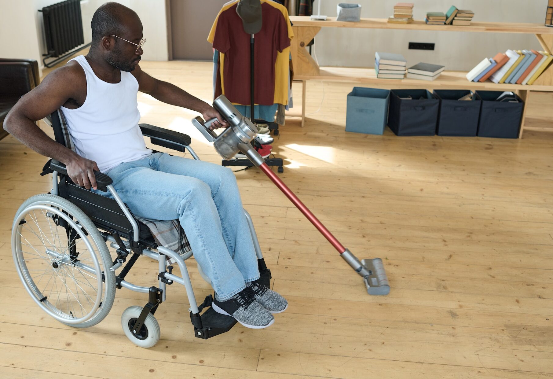 Disabled man cleaning room with vacuum