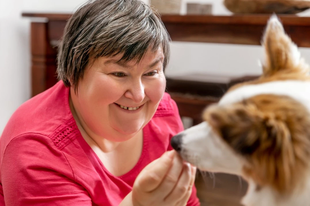 Disabled woman smiling and giving her dog a snack