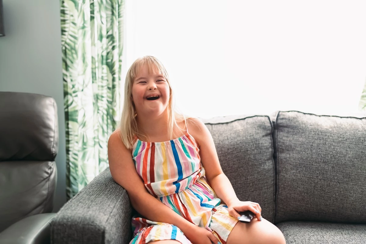 Disabled girl laughing while sitting on couch