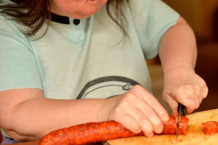 Woman with down syndrome cutting carrots in kitchen