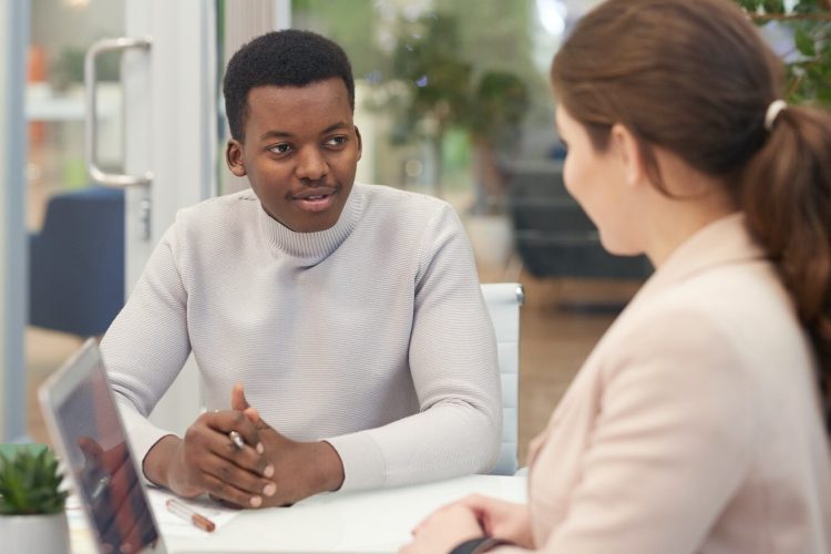 Disabled man talking to support worker at desk
